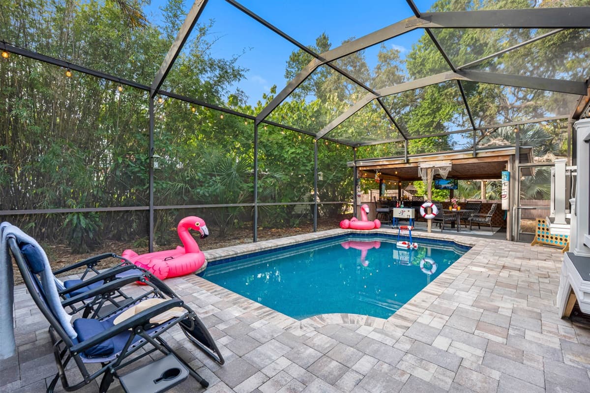 Enjoy this inviting pool oasis featuring comfortable lounge chairs, fun flamingo floats, and a fully screened enclosure for year-round comfort.