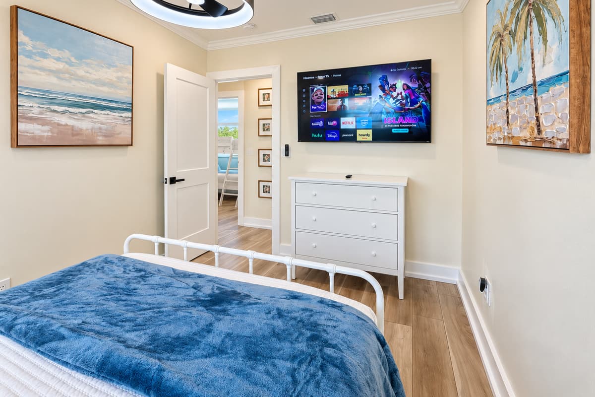 Queen bedroom with a white metal bed frame and smart TV.