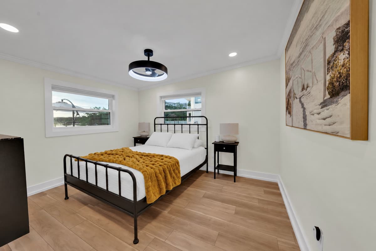 A cozy queen room with a modern touch. A queen bed with a black metal frame, a chunky mustard throw and natural light from two windows. Comfortable, stylish and quiet.