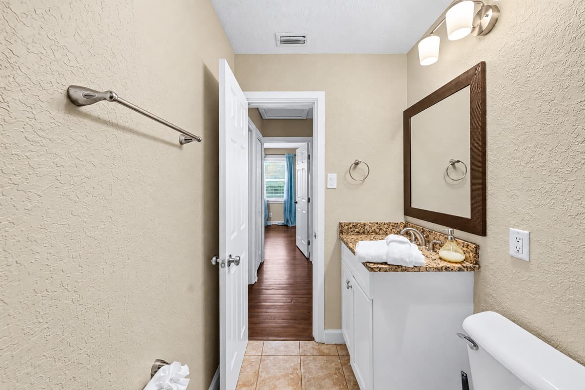 Bathroom vanity area with mirror and storage, conveniently located near bedrooms.