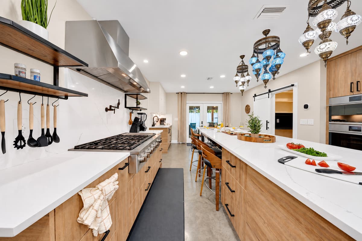 Professional range, wall ovens, room for two cooks. Pot filler over the burners, hood above and counter on both sides — this kitchen was built for feeding eighteen, not four.