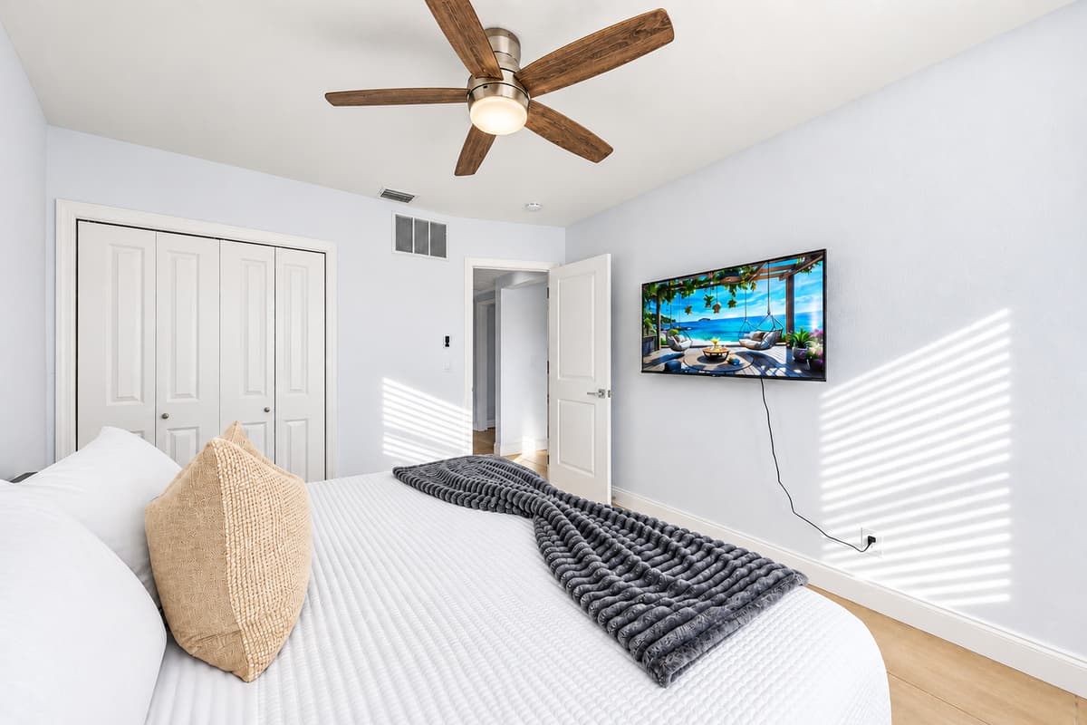 Bright guest bedroom featuring plush bedding, TV, and clean contemporary styling.