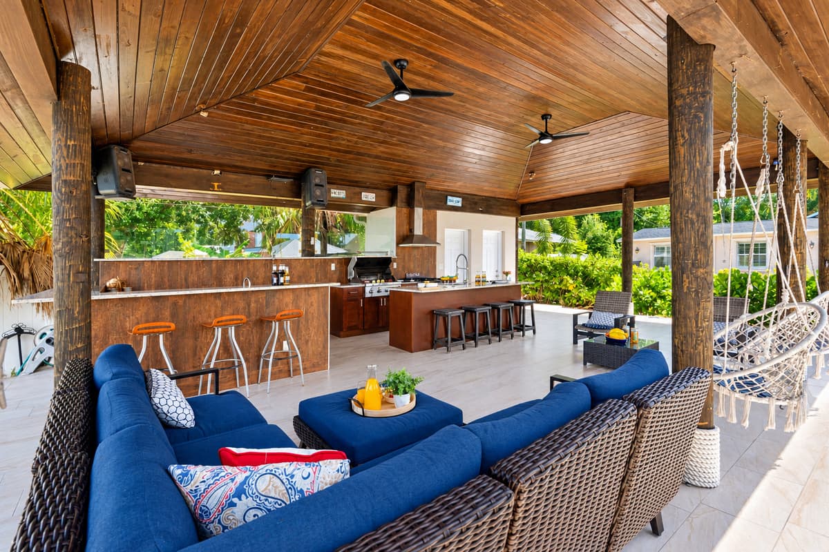 Enjoy serene water views from this beautifully landscaped backyard featuring swaying palm trees, vibrant flowers, and a spacious covered outdoor kitchen.