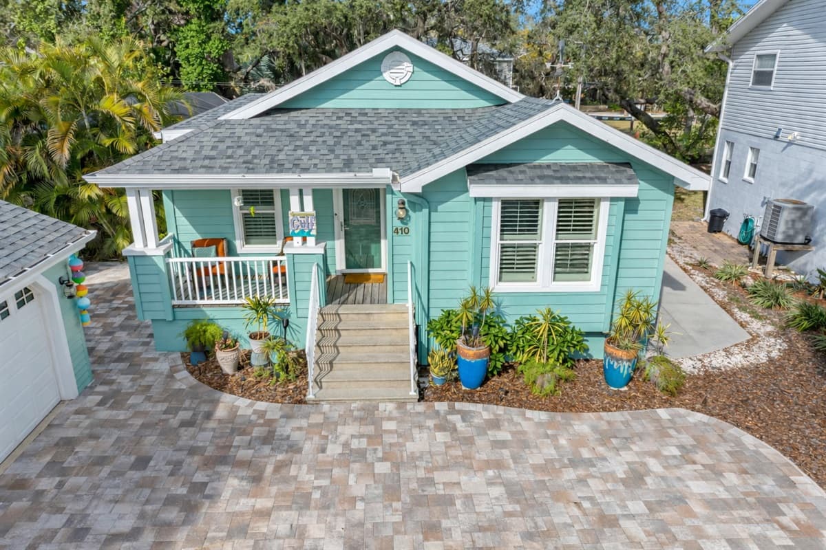 The coastal-inspired exterior features crisp white accents, colorful decor, and a beautifully kept front entry.
