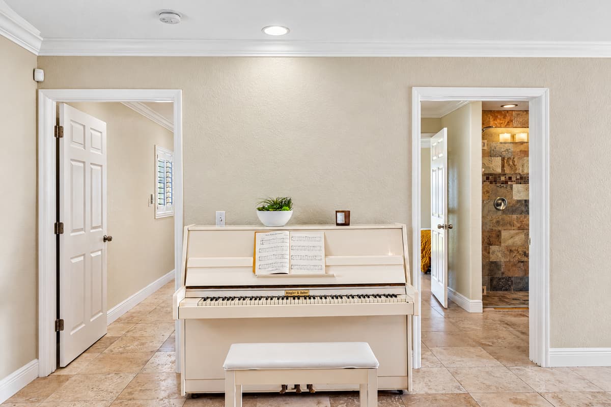 This inviting space features a white upright piano and matching bench, ready for a relaxing play session.