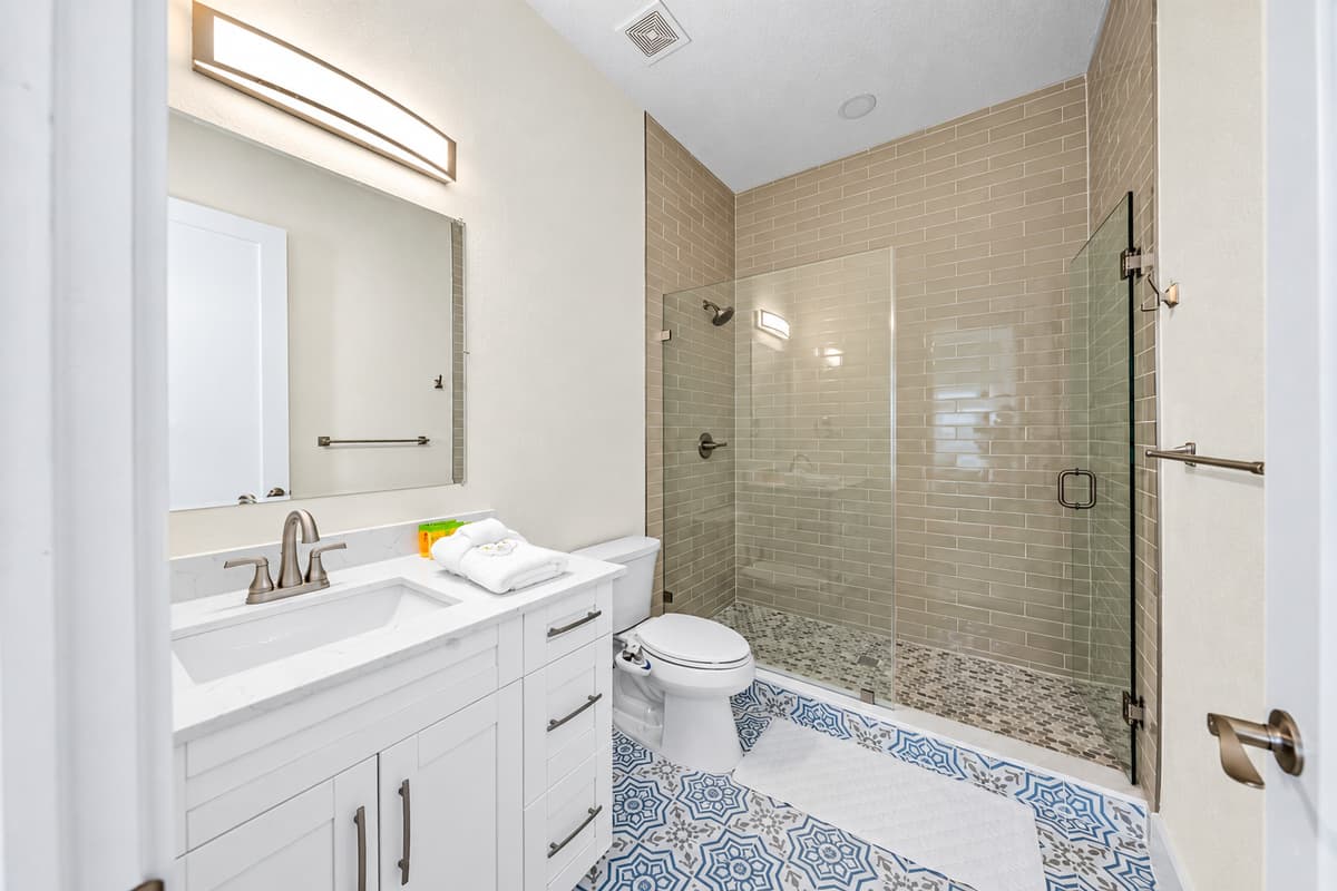 No more waiting in line for the shower. A walk-in rain shower with glass door, a wide vanity, and blue patterned tile floors. With three full bathrooms, mornings run smoothly even when all 9 guests need to get ready at once.