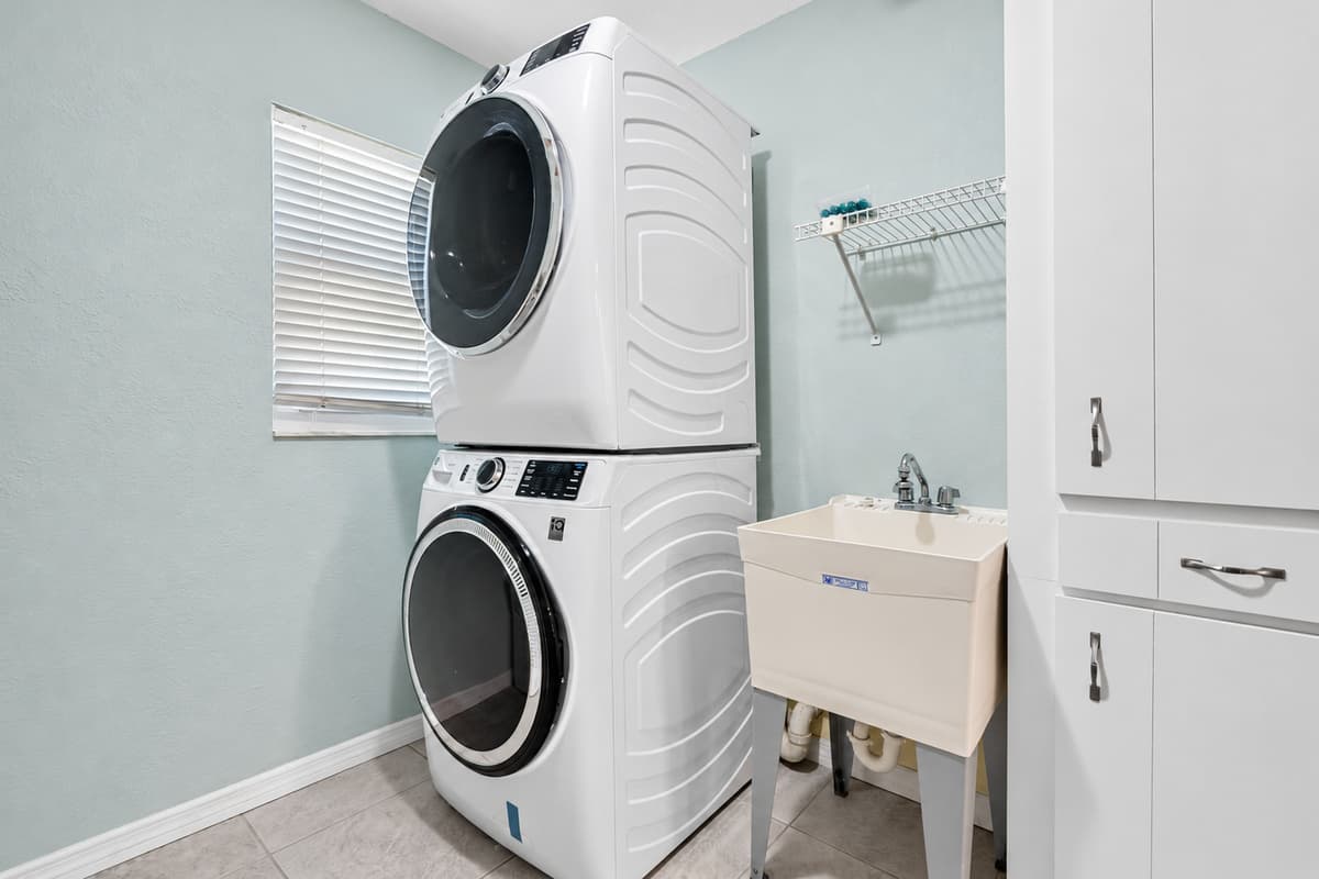 Designed for comfort and convenience, this laundry area features a modern front-load washer and dryer plus a deep sink for all your cleaning needs.