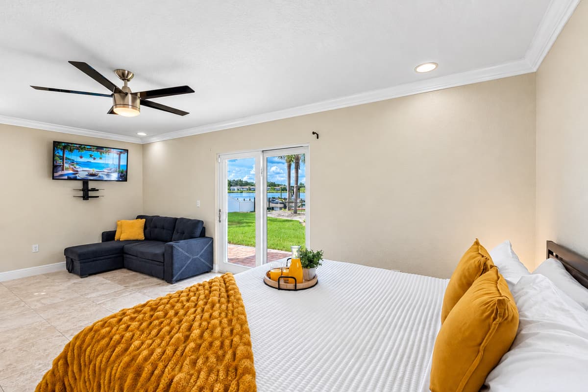 Wake up to serene water views in this airy bedroom, featuring sliding glass doors that open directly to the lush backyard and waterfront.