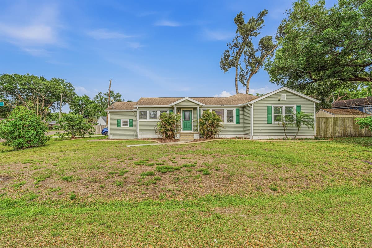 Wide view of the property showcasing large yard space and curb appeal in a quiet neighborhood.