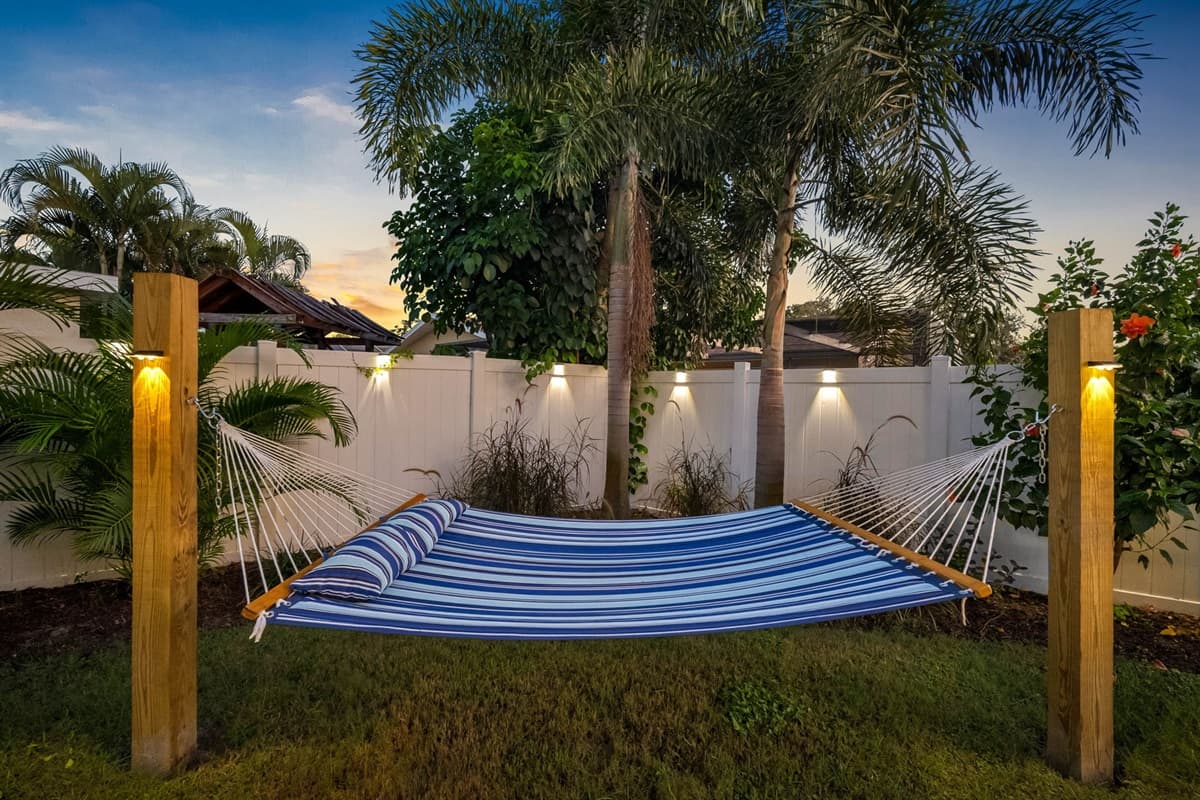 Soft lighting, swaying palms, and a comfortable hammock make this backyard an idyllic spot for unwinding after a day at the beach.