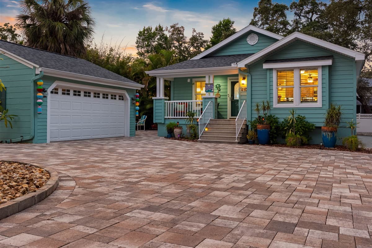 This home’s exterior blends tropical landscaping with a soft teal color scheme and a spacious, clean driveway.
