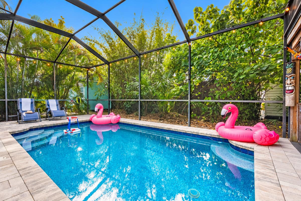 Relax by the crystal-clear pool in a private, screened-in setting surrounded by mature tropical plants.
