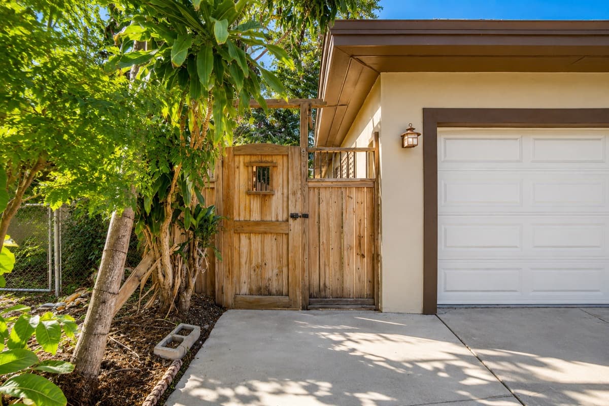 Private side entrance and garage area surrounded by lush tropical greenery.