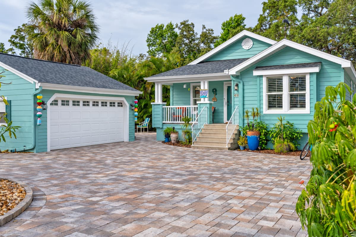 This charming coastal-style home features a mint-green exterior, inviting front porch, and beautifully landscaped entryway.