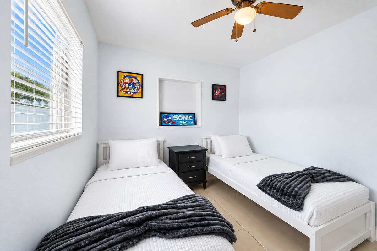 Bright guest room with two twin beds, stylish bedding, and sunny window views.