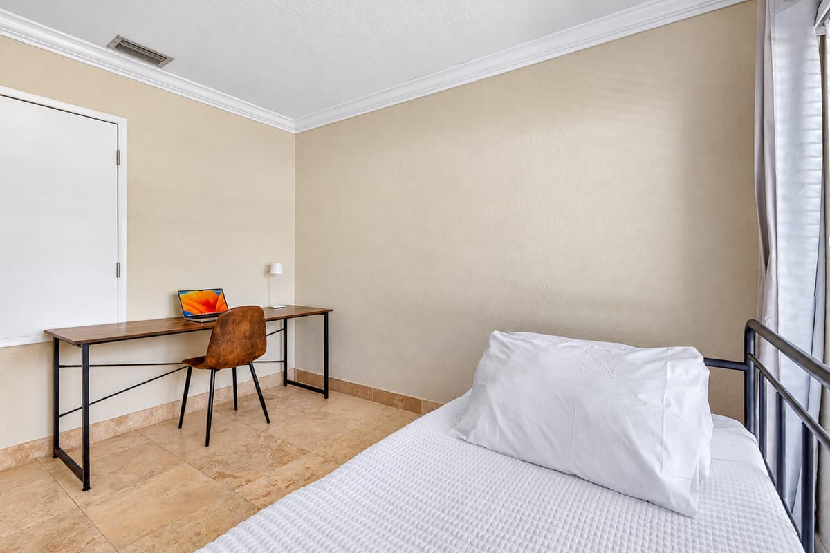 A sunny room offering both a comfortable daybed and a dedicated work desk, ideal for remote work or study.