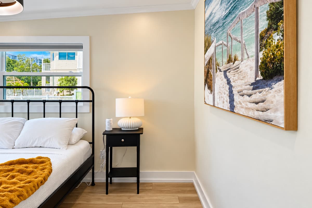 Queen bedroom with a black metal bed frame and mustard throw.