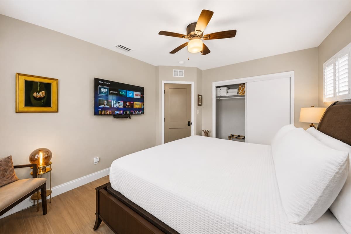 Spacious and inviting king bedroom featuring a smart TV, cozy seating area, and warm modern décor.