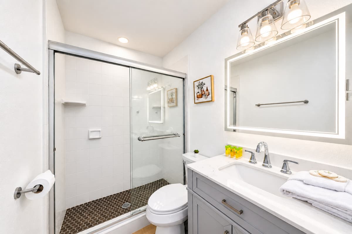 A second full bath means nobody waits in the hall. Glass shower, wide vanity, warm lighting and room to get ready without an audience. Mornings move fast when the group is not taking turns.