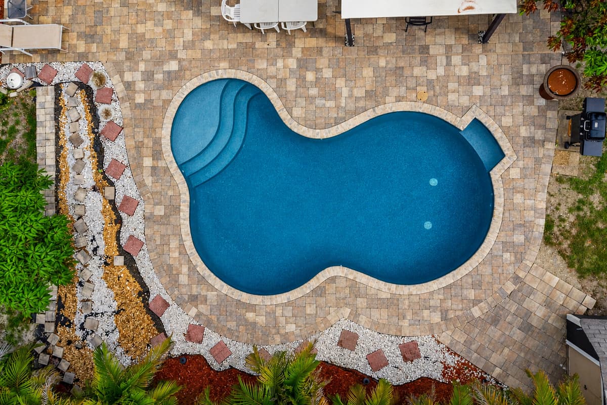 Unique overhead view highlighting the pool’s inviting shape and expansive paver deck.