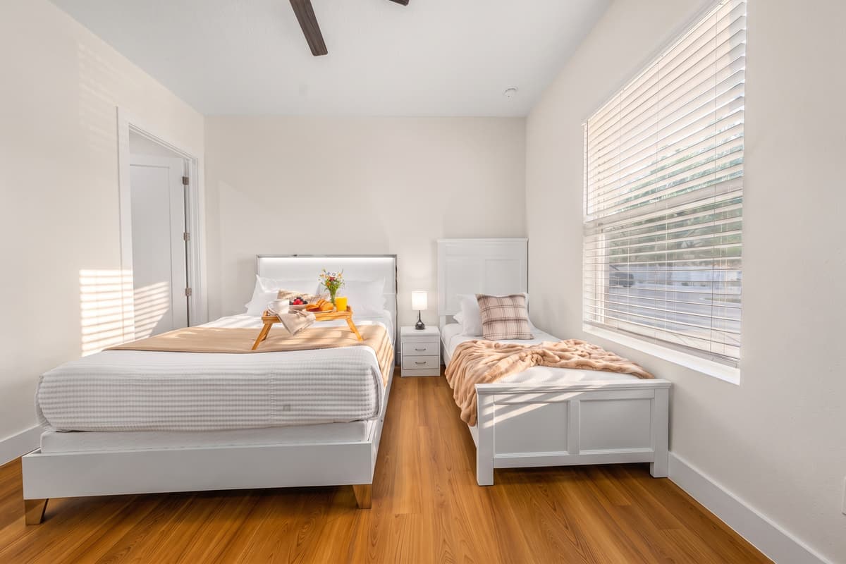 Two beds in one bright room, sleeps three comfortably, with fresh linens and morning light.