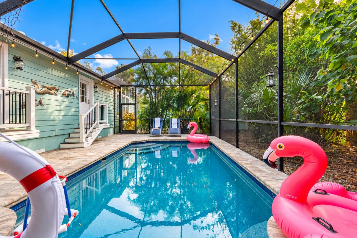 The screened-in pool area blends comfort and fun with loungers, flamingo floats, and a relaxing outdoor living setup.