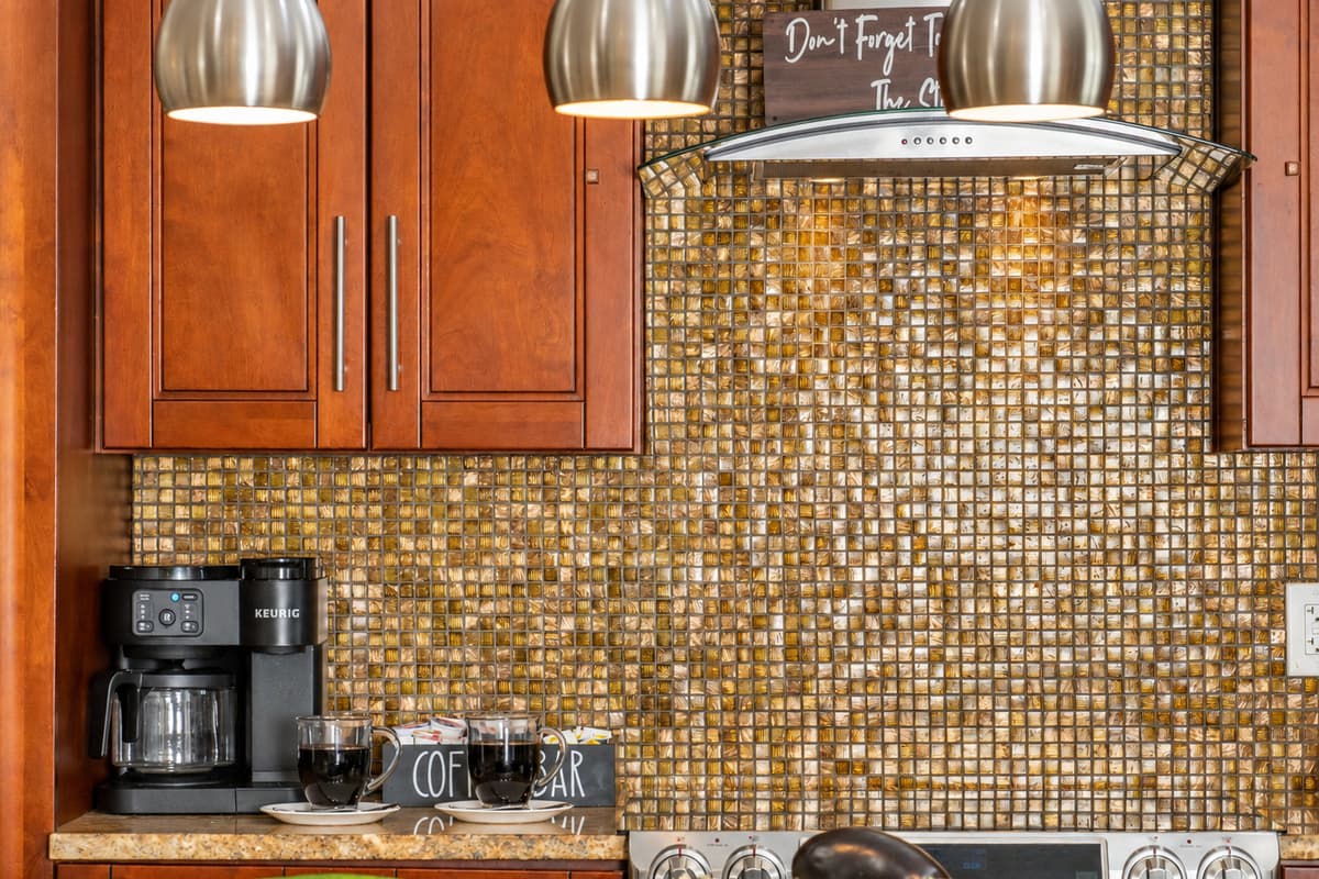 The rich wood cabinets and gold-hued surfaces pair beautifully with contemporary stainless fixtures for a balanced, stylish kitchen.