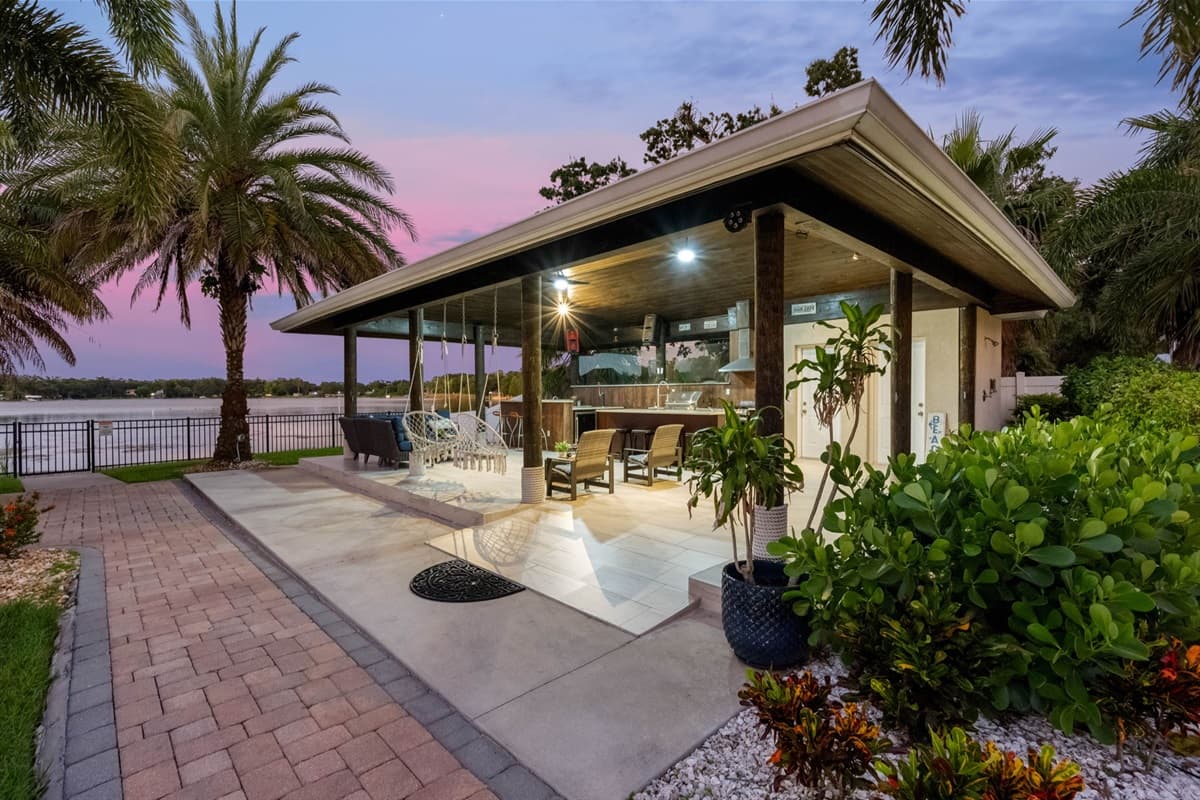 This expansive covered patio offers bar seating, hanging chairs, and lounge areas, all with stunning waterfront views.