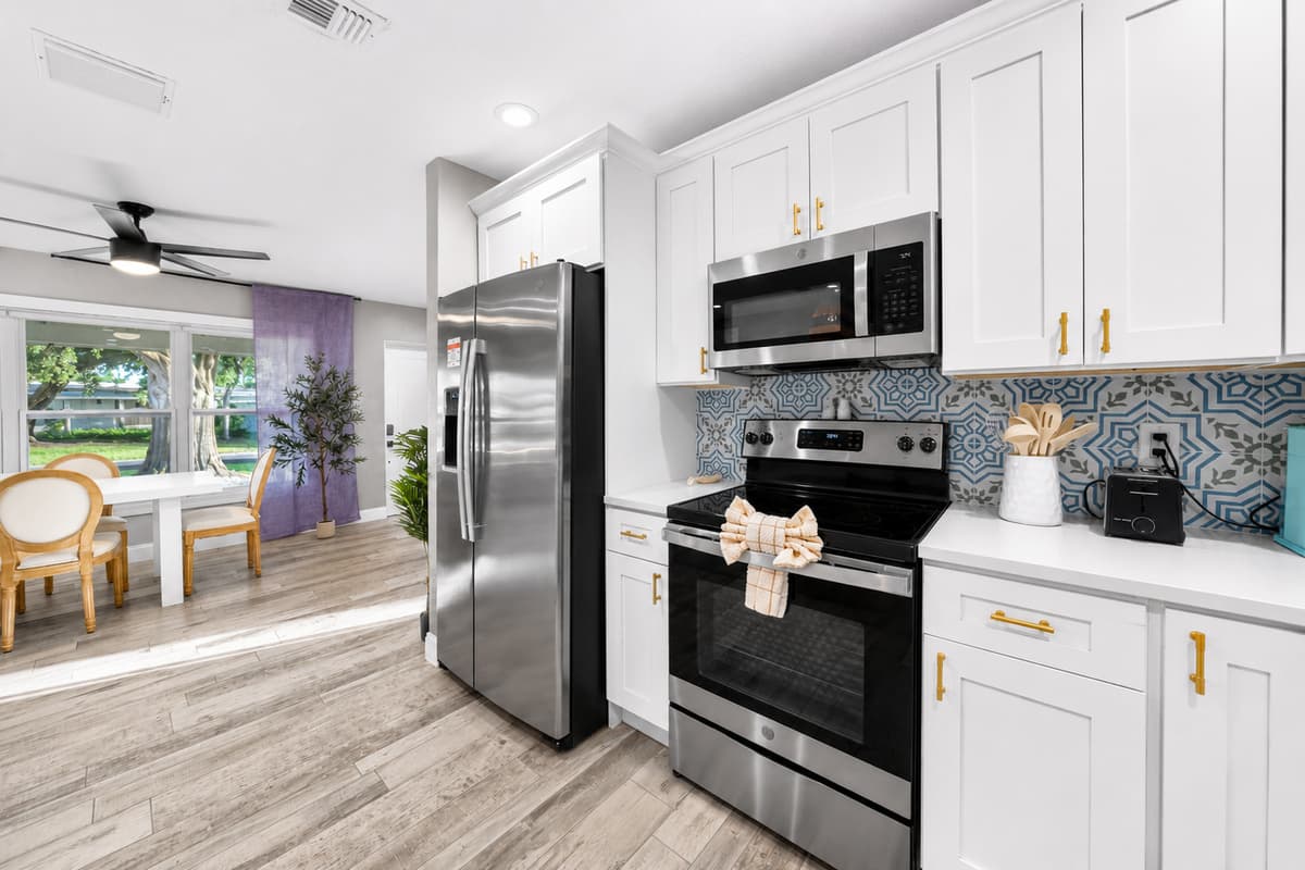 Kitchen workspace with stainless steel refrigerator, range, microwave, and ample cabinetry, opening directly into the dining area.