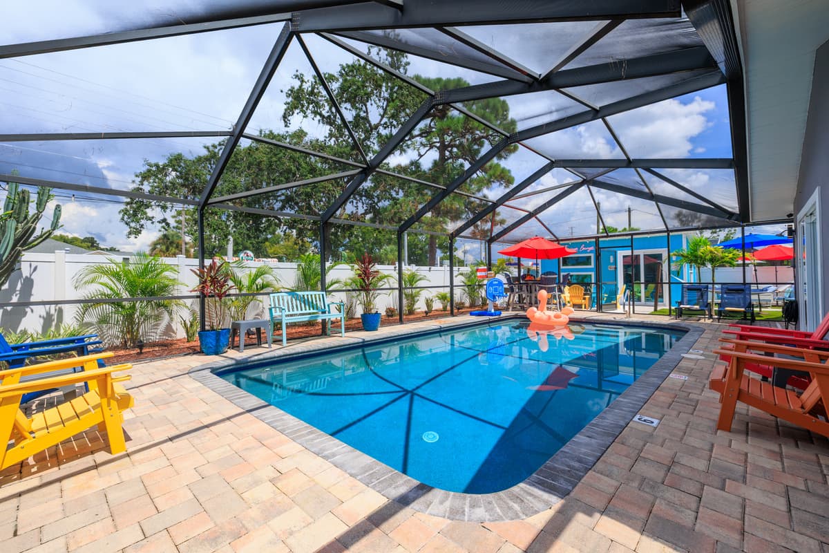 Screened-in pool with sunny lounge seating and outdoor dining.