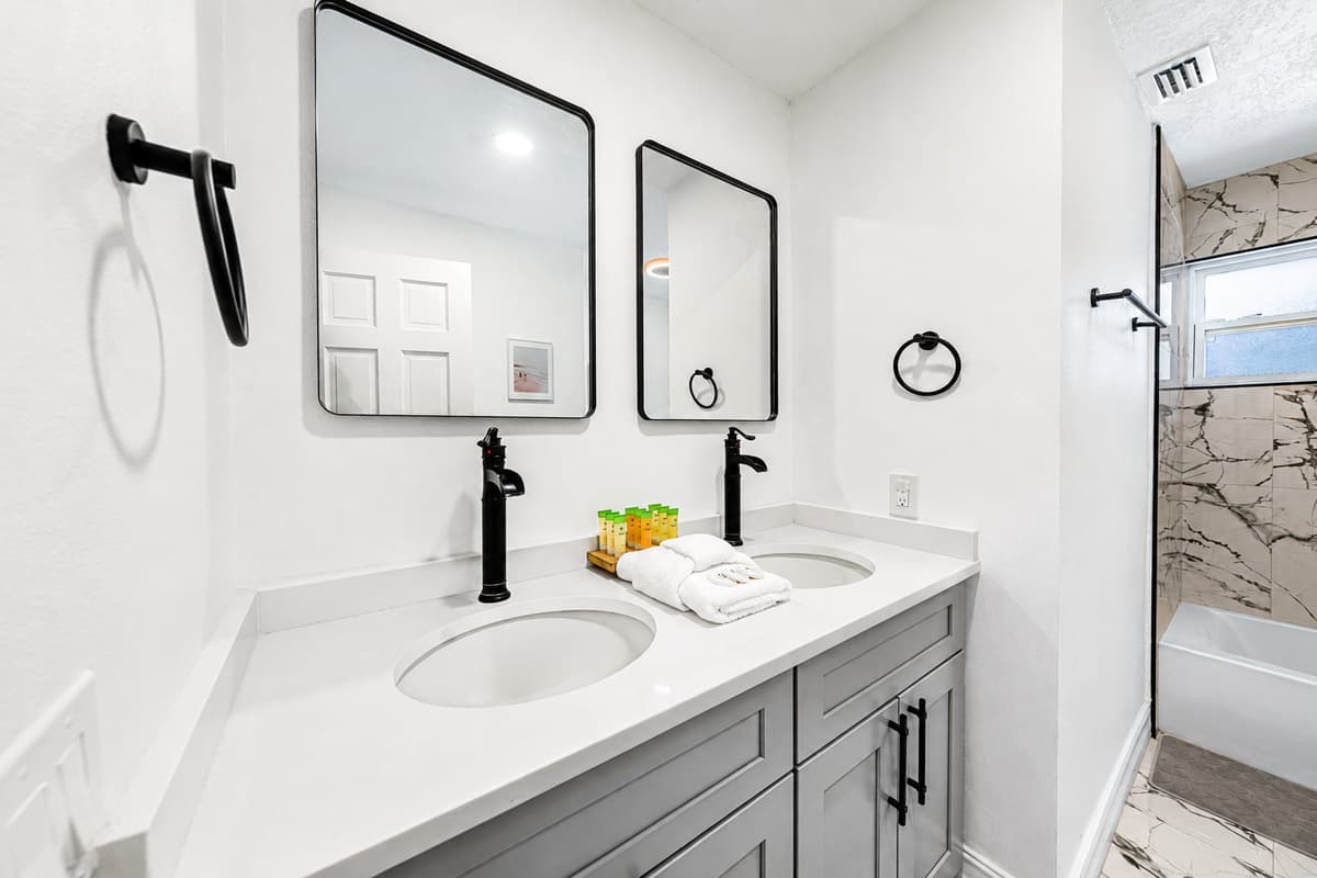 Marble tile, black fixtures, counter space for both toothbrush cups. Getting ready happens in parallel.