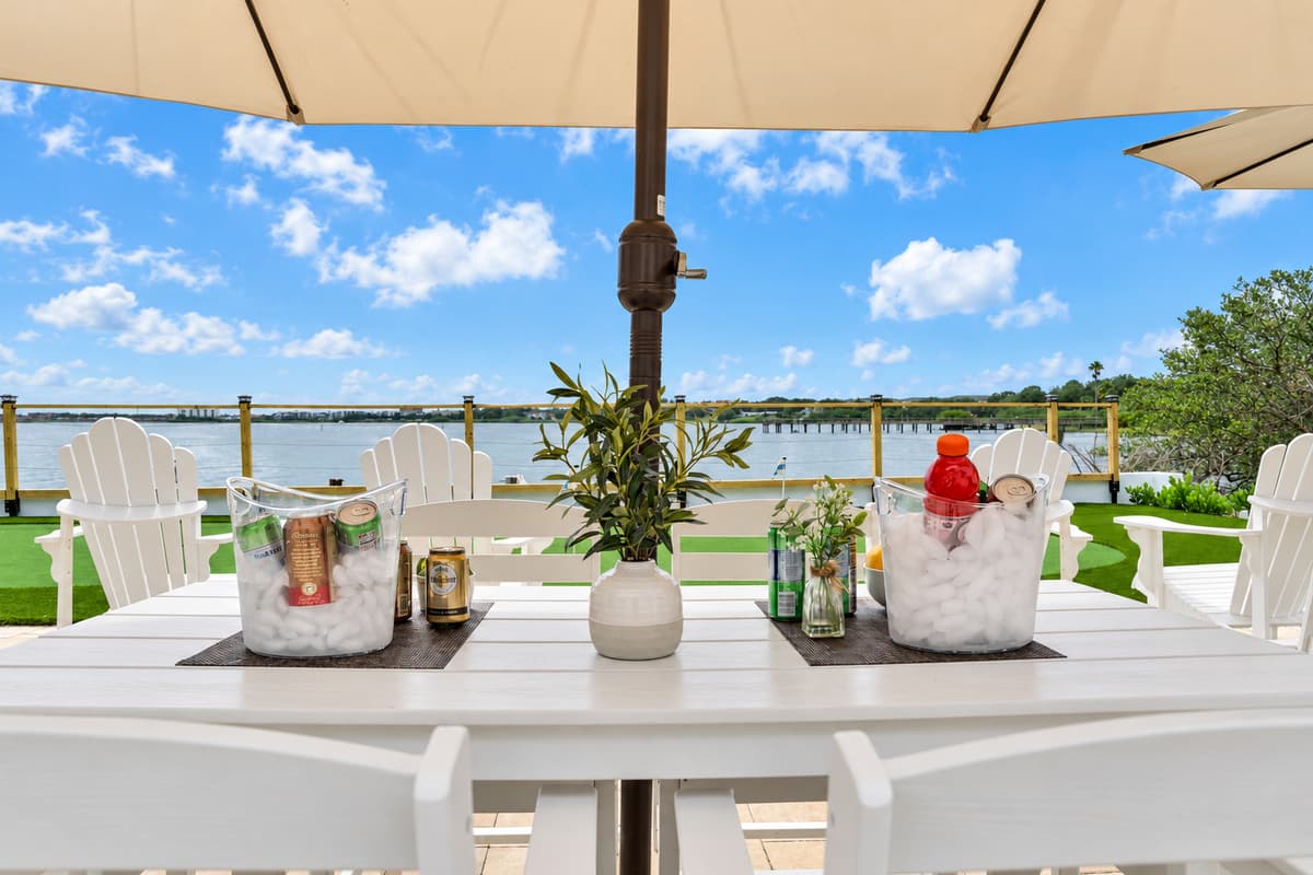 Drinks on ice, water views on tap. A bucket of cold drinks on the patio table under the umbrella, with the bay just beyond. Happy hour practically plans itself.