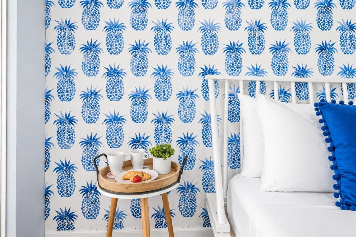 Charming coastal-themed corner with playful pineapple wallpaper and stylish bedside setup. (Decorative food setup for staging purposes only)