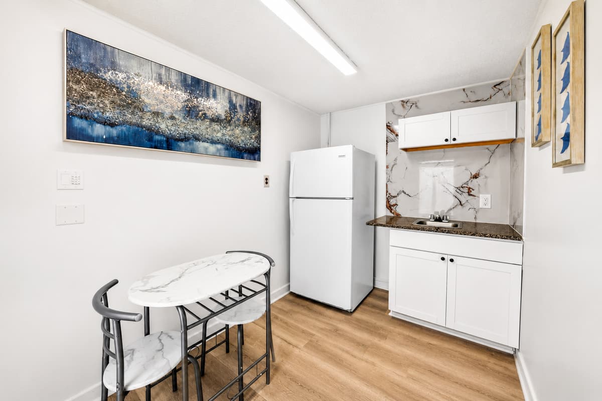 Cozy studio dining nook and kitchenette with refrigerator, sink, storage space, and seating for two, creating a private retreat within the property.