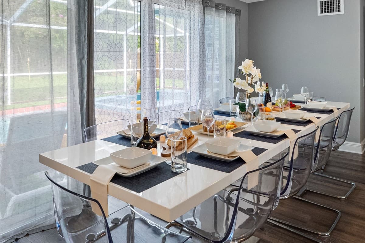 With its glossy white dining table and acrylic chairs, this space exudes a clean, minimalist vibe that complements the home’s modern aesthetic.