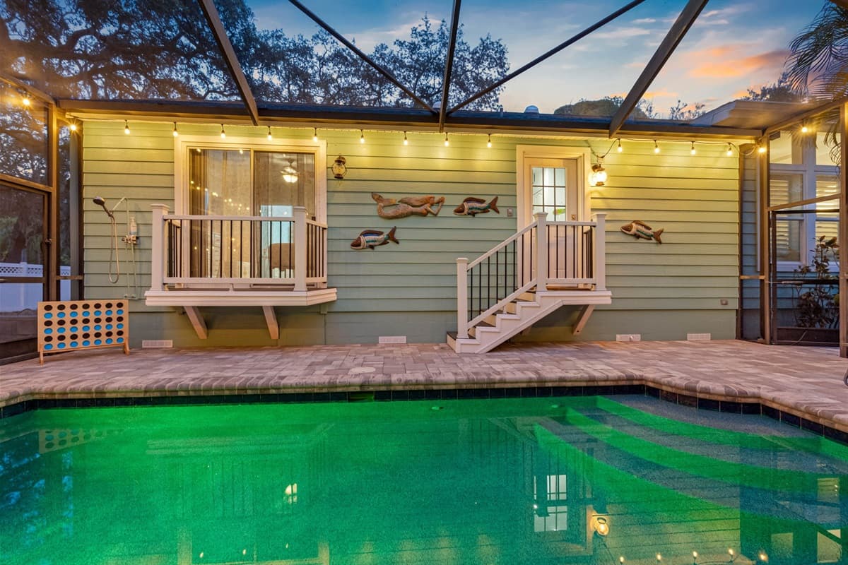 Swim or relax in this private pool oasis featuring soft lighting, tropical surroundings, and an easy transition to the outdoor entertainment area.