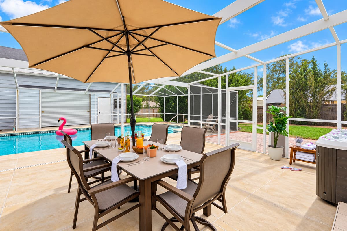 Dine al fresco in this spacious screened patio, featuring a large outdoor dining table and relaxing poolside views.