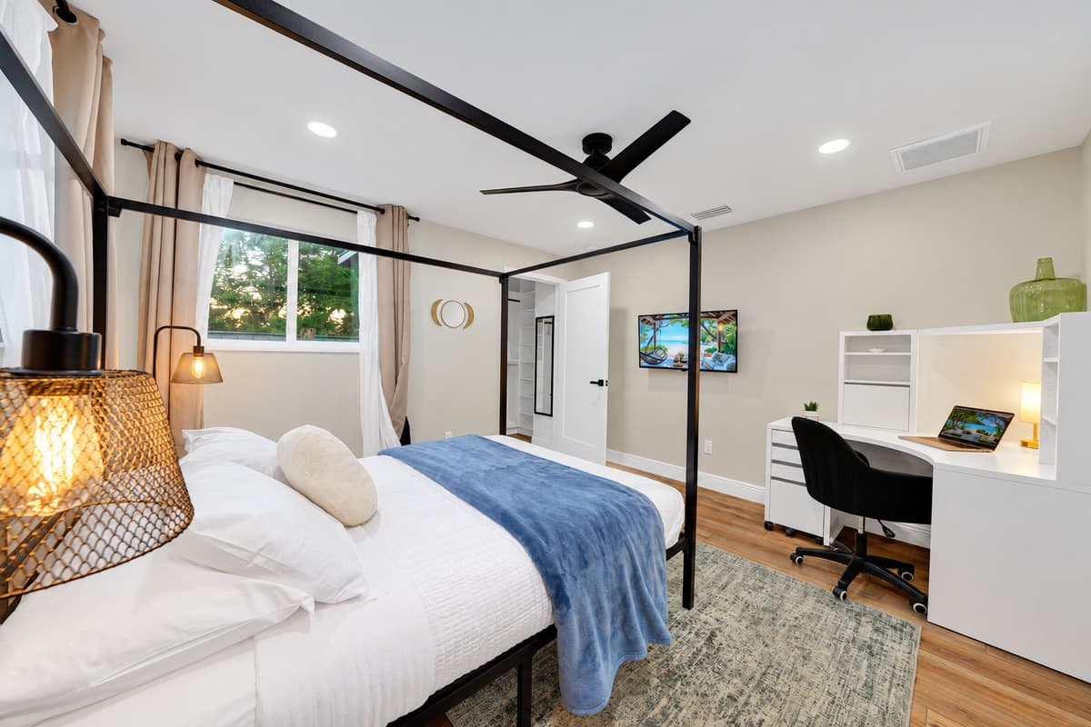 The suite that quietly wins the coin toss. Canopy king bed, warm pendant lighting, a private desk and a smart TV — the room everyone hopes gets assigned to them when the group divides up on arrival.