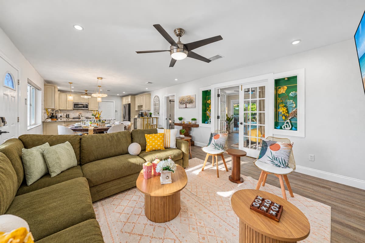 An open-concept living area filled with natural light, featuring a large sectional, accent chairs, and a sleek entertainment setup for laid-back evenings.