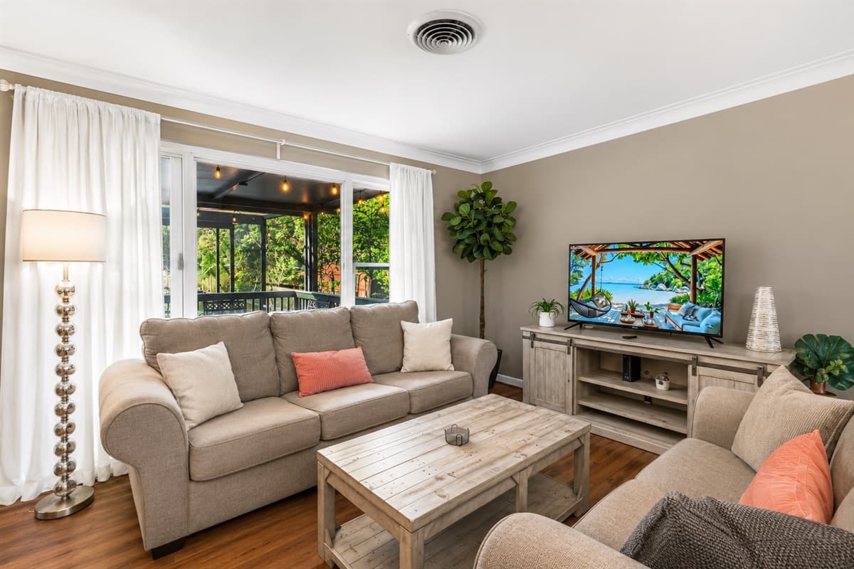 Cozy lounge space with warm lighting, comfortable couches, and backyard views through large windows.