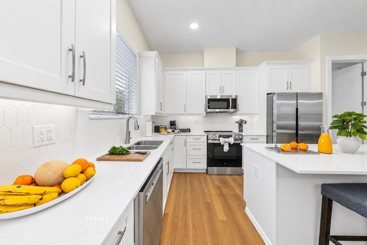 Full kitchen with quartz counters, stainless appliances, cookware, dishes, and a coffee setup.