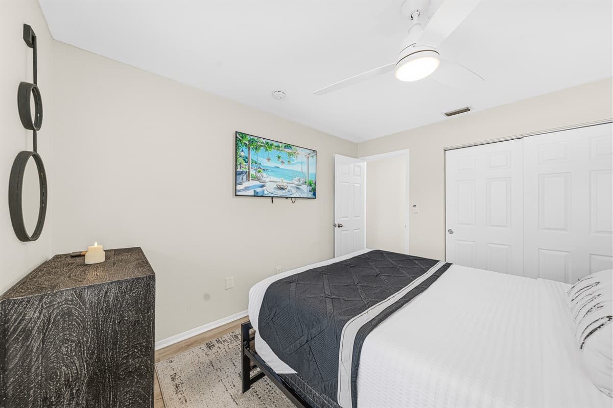 Spacious guest bedroom featuring a queen bed, Smart TV, and ample storage.