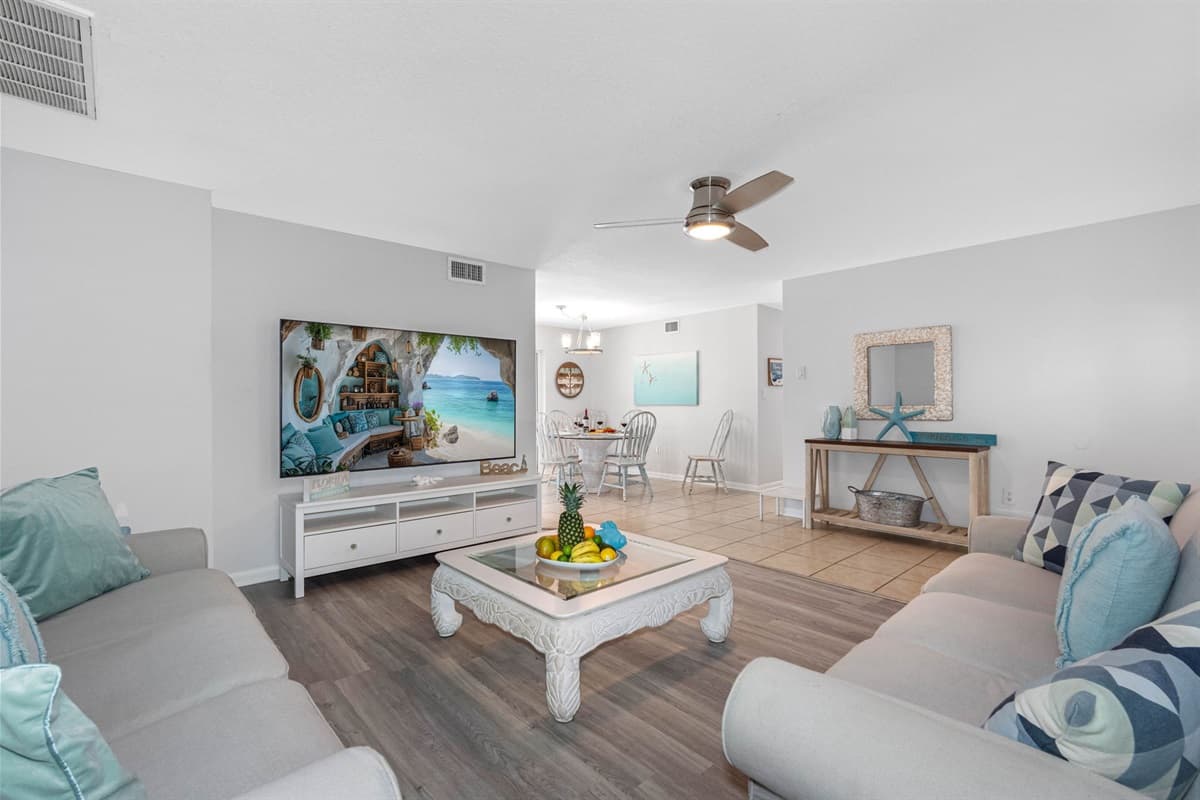 At the heart of the living area is a large, ultra-comfortable couch, adorned with decorative pillows that feature soft, beachy tones and playful coastal motifs, adding a touch of seaside flair.