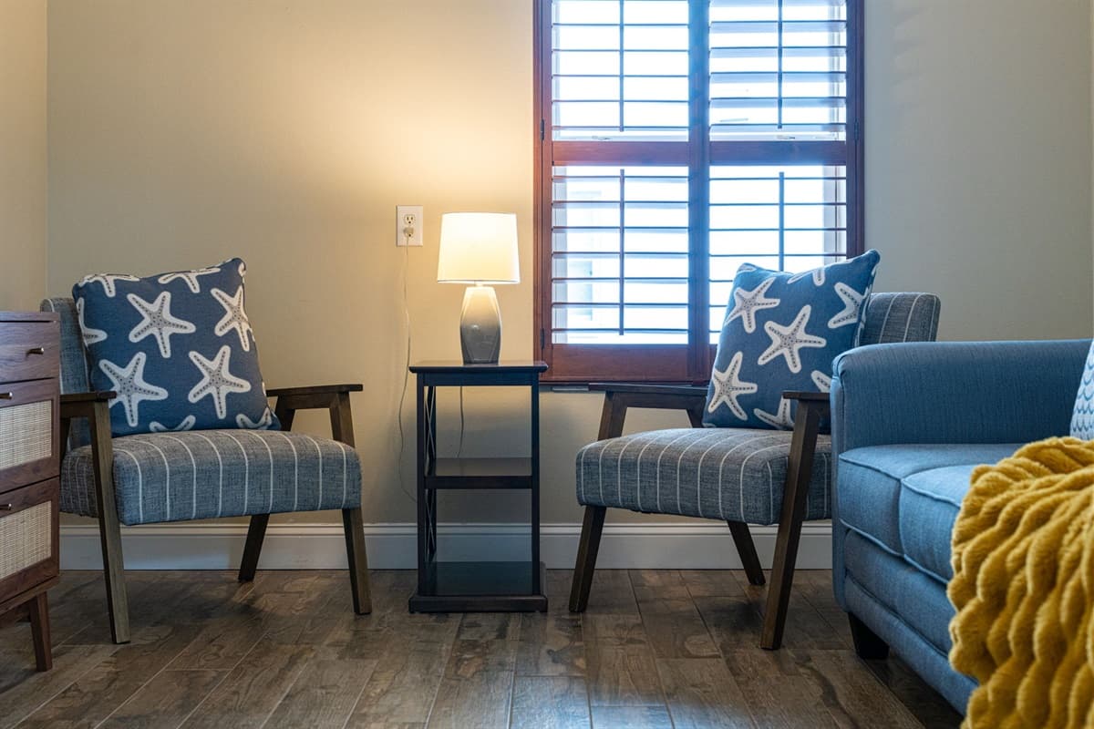 This charming guest bedroom offers a comfortable pullout sofa bed, blending function and style. Warm wood flooring, soft textiles, and natural light create a serene and restful atmosphere.