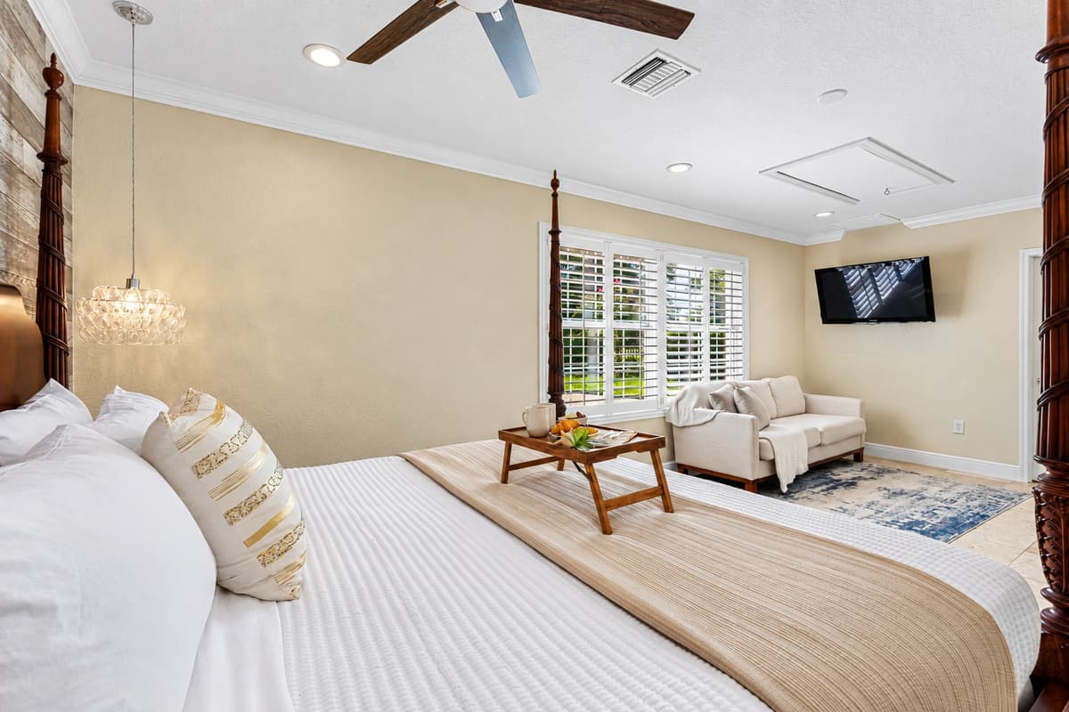 Elegant and serene, this bedroom combines a classic wooden bed frame with a cozy seating area, perfect for unwinding with a book or TV.