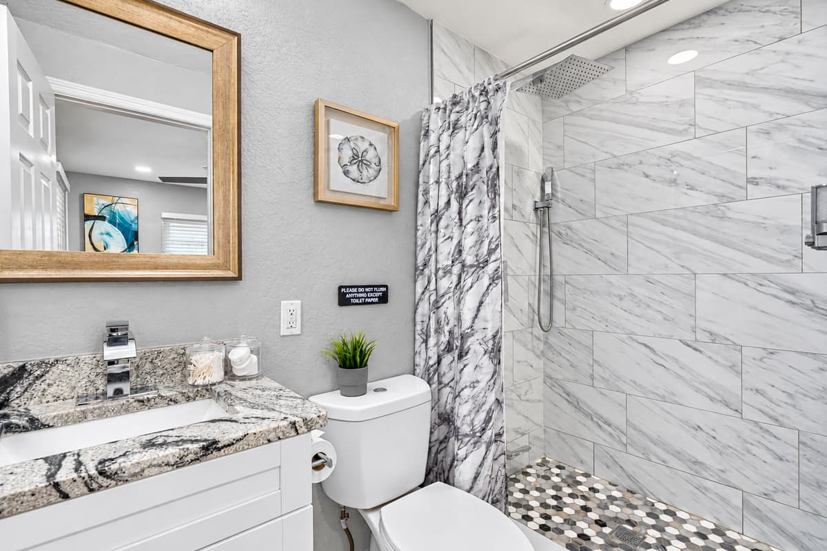 Walk-in shower for quick morning routines. The second full bathroom has a walk-in shower with a pebble-tile floor and a granite vanity. It serves the queen and bunk rooms, keeping mornings moving.
