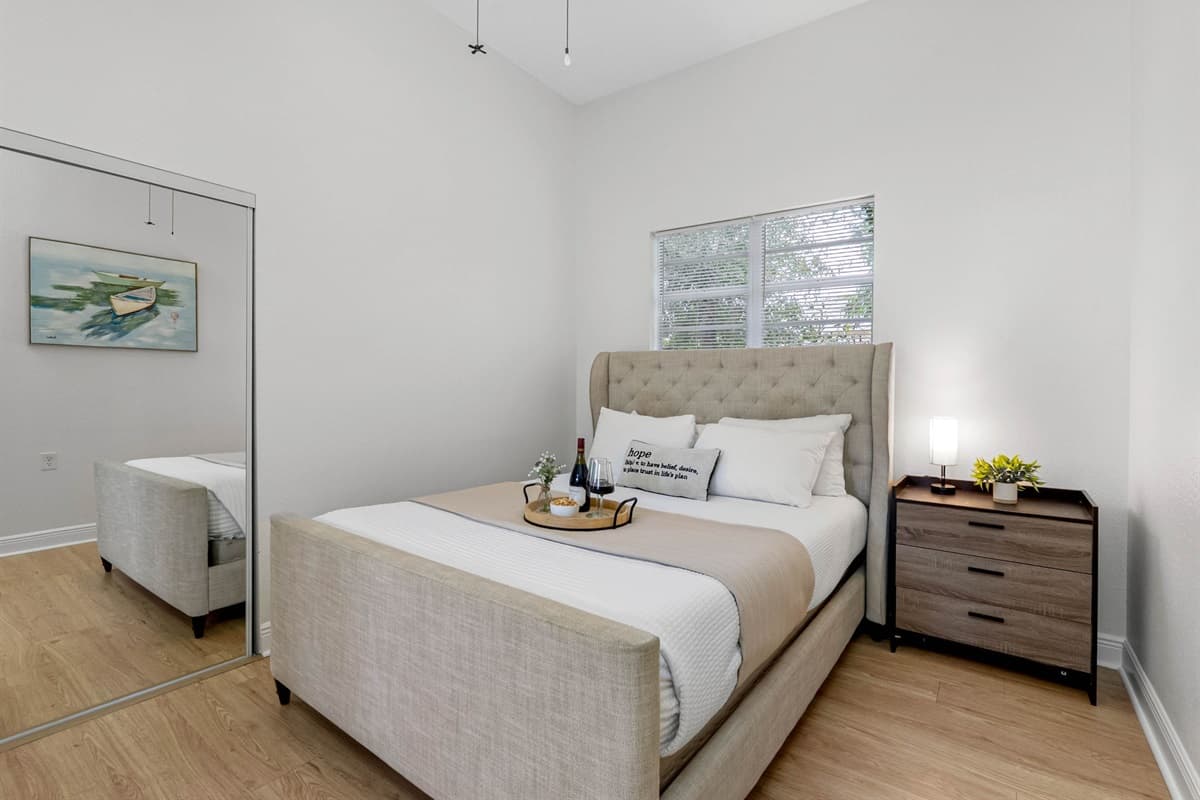 This spacious bedroom features a plush upholstered bed, soft neutral tones, and abundant natural light, creating a calm and inviting space to unwind after a day of exploring.