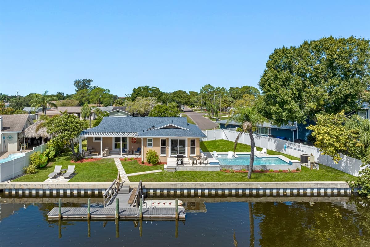 Aerial back view of the property showcasing the beautiful heated pool and access to dock in the lake. Don't miss the opportunity and book now!