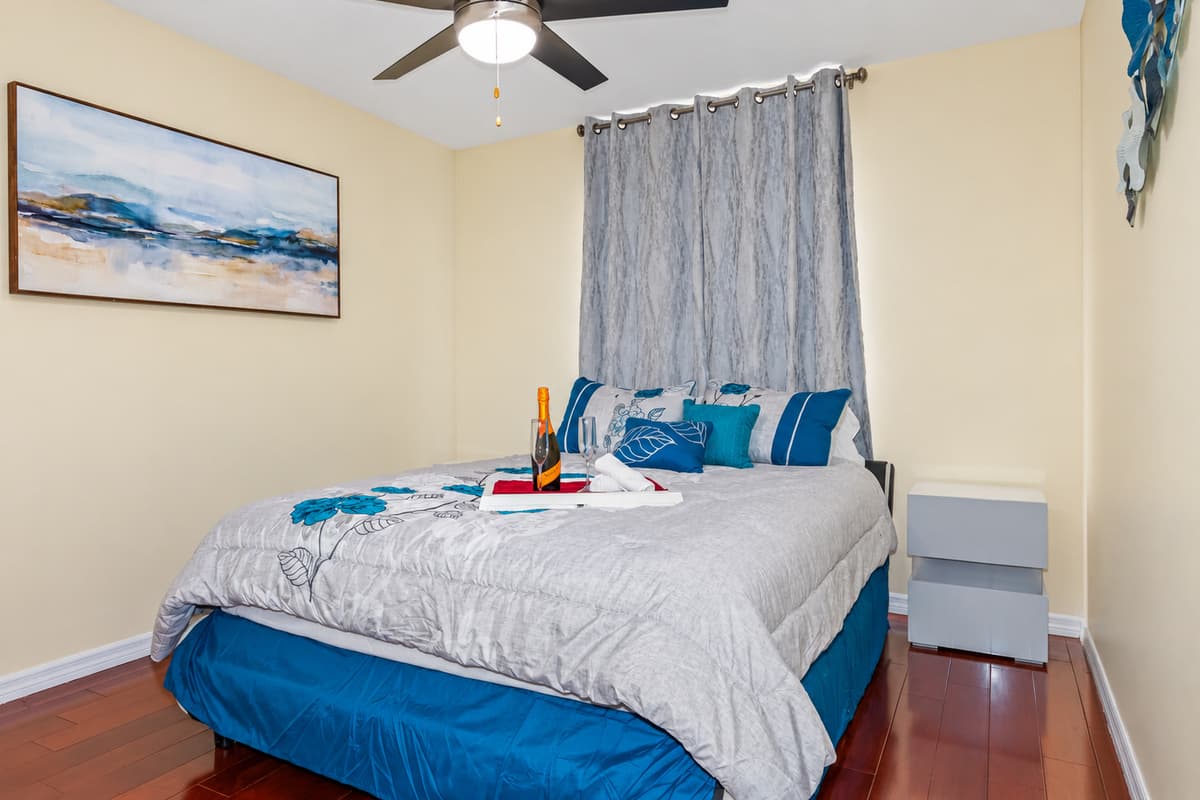 On the left side of the bed, is a white bedside table providing a convenient and stylish spot for the night lamp, books, and other bedtime essentials.