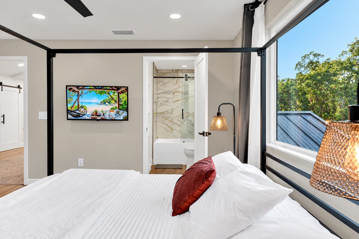 Bed, screen and your own bathroom door. Bright, high-ceilinged and quiet, with green outside the window and warm light for reading. The suite you settle into and never quite leave.